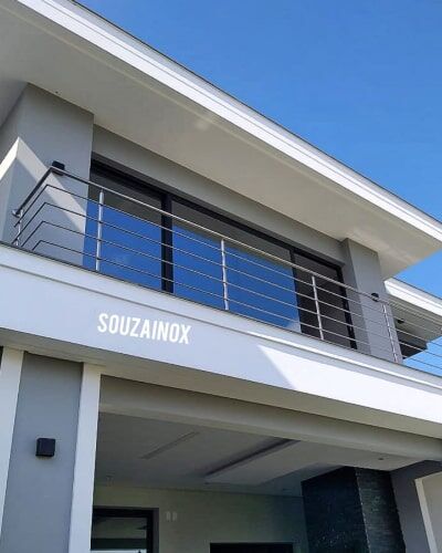 Guarda corpo de aço inox com vidro instalado em sacada com vista para o mar